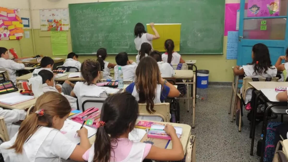 Profesora explicando lección a estudiantes pequeños en escuela de gestión oficial
