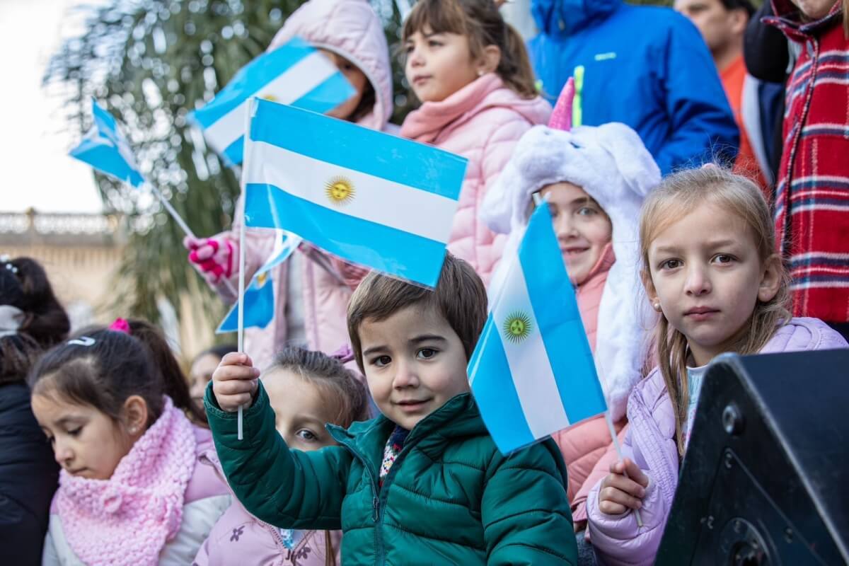Chicos celebrando con banderas argentinas el Día de la Patria en Santa Fe durante el aniversario de la Revolución de Mayo