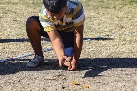 Niño jugando al tradicional juego de las bolitas en el suelo