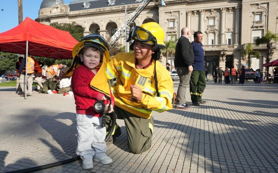 Bombero voluntario junto a un niño en la muestrar realizada en plaza 25 de Mayo en Santa Fe en el marco de la Semana del Bombero Voluntario