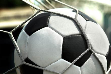Pelota de fútbol atrapada en la red de un arco tras un gol