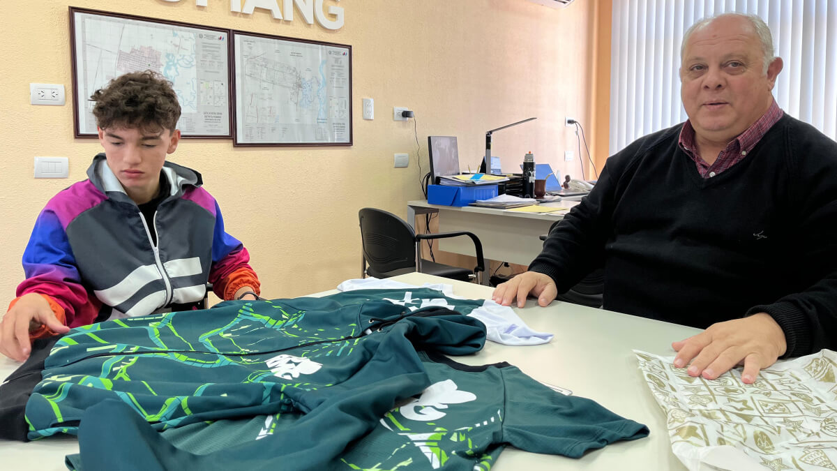 El intendente de Romang, Sergio Ramseyer, posa junto al joven atleta Valentino Molina, quien sostiene indumentaria deportiva.