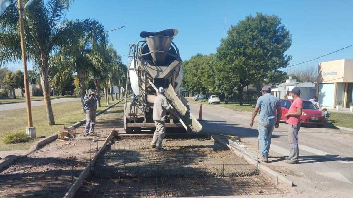 Empleados municipales trabajando en la instalación de reductores de velocidad en la Ruta 40, utilizando maquinaria y materiales de construcción