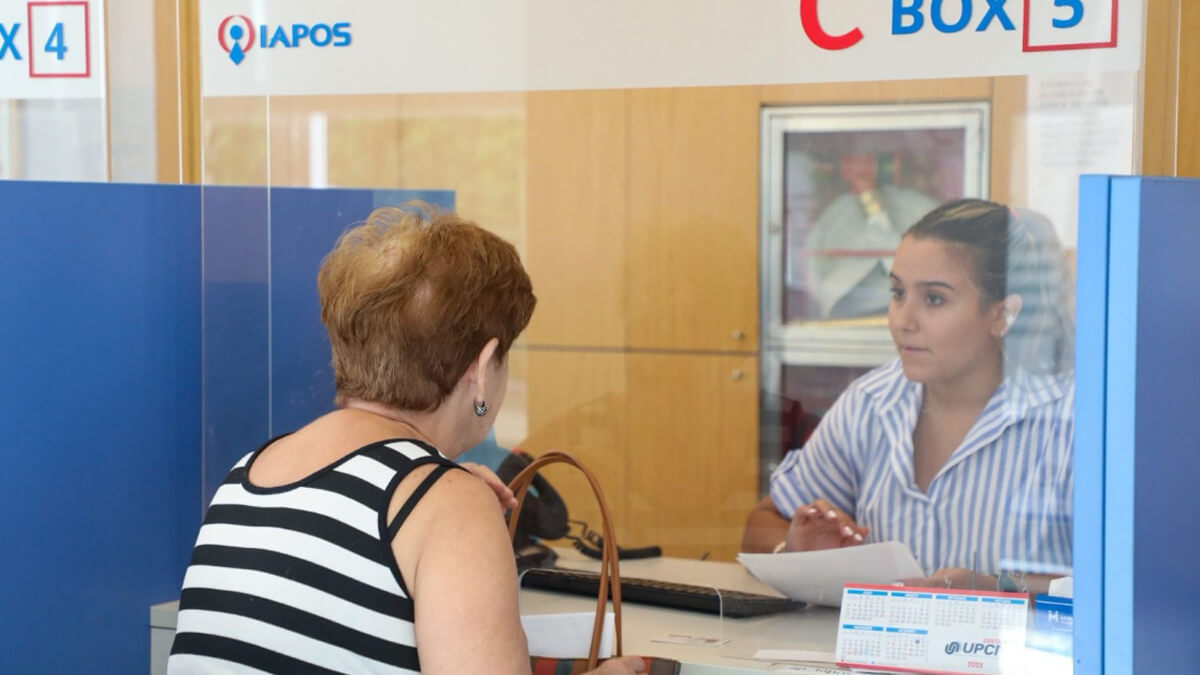 Afiliado jubilado realizando una consulta en las oficinas de IAPOS, recibiendo asesoramiento sobre el nuevo beneficio de compensación de medicamentos.