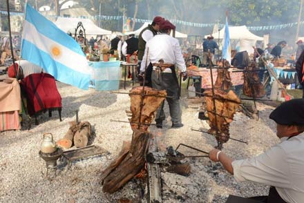 Asado a la estaca en los festejos tradicionales por el Día de la Bandera en Rosario, con familias disfrutando de la gastronomía regional y el ambiente festivo.