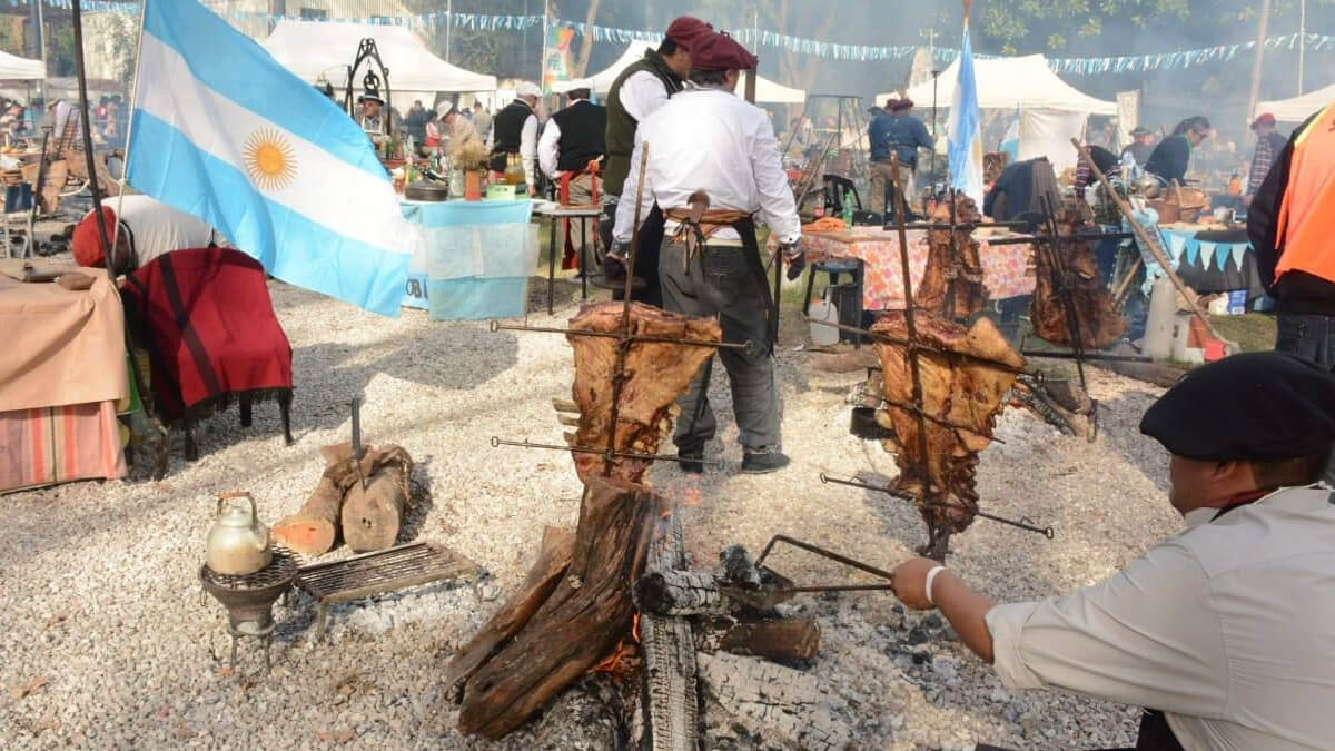 Asado a la estaca en los festejos tradicionales por el Día de la Bandera en Rosario, con familias disfrutando de la gastronomía regional y el ambiente festivo.