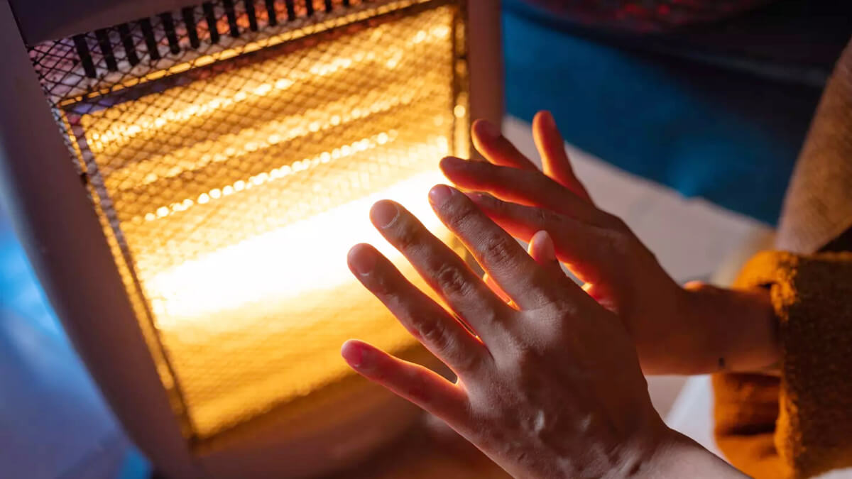 Persona utilizando estufa calefactor eléctrica en un ambiente cálido para ilustrar el uso de energía en invierno