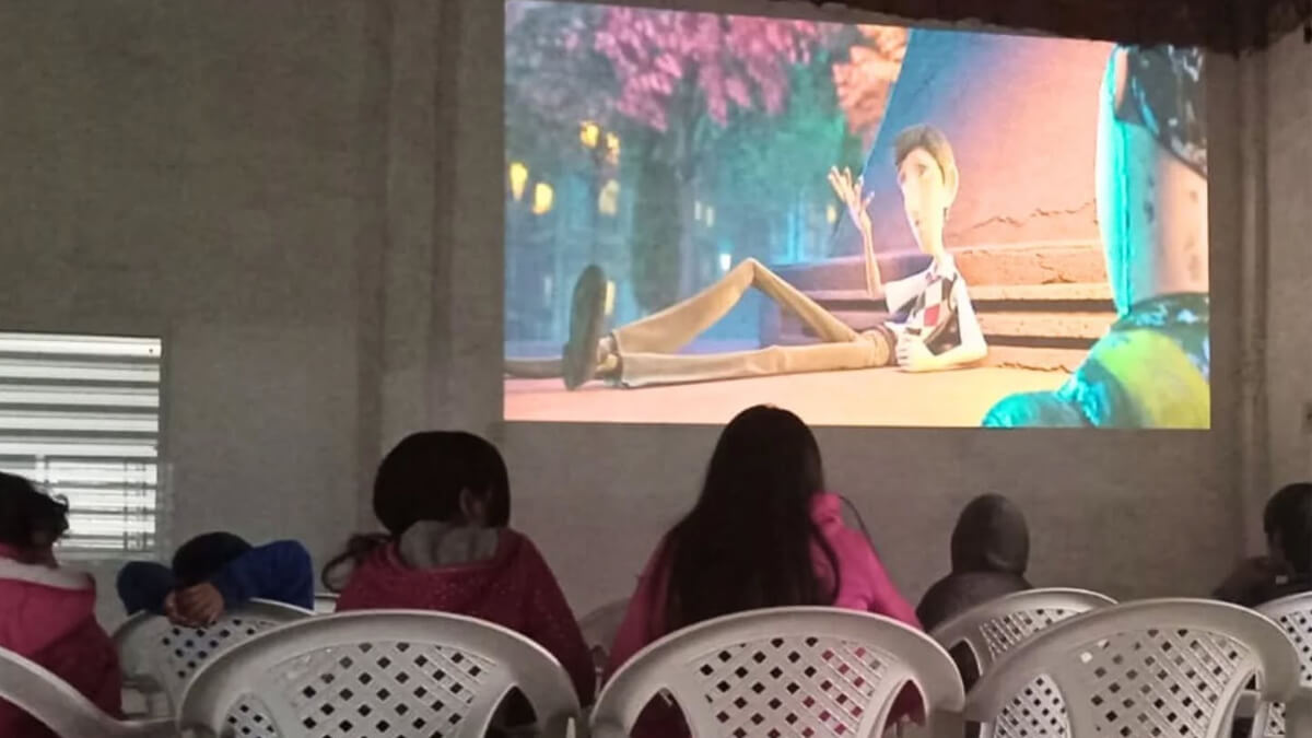 Niños de Guadalupe Norte disfrutando la película Metegol durante una jornada recreativa.