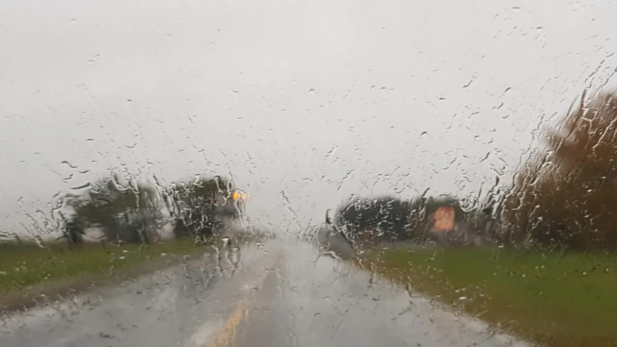 Día lluvioso visto a través del vidrio de un auto con gotas de lluvia
