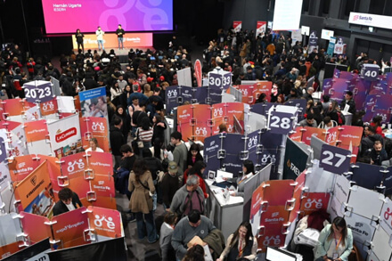 Participantes recorriendo la primera edición de Expo Empleo en Santa Fe, con stands de empresas y postulantes en entrevistas laborales.