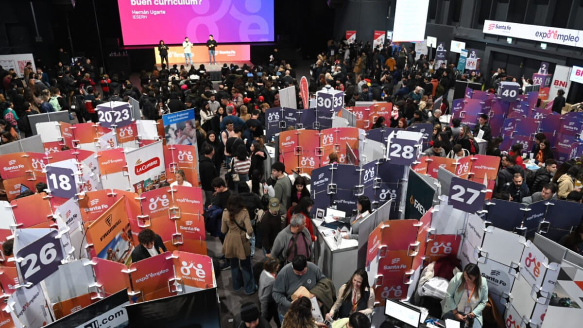 Participantes recorriendo la primera edición de Expo Empleo en Santa Fe, con stands de empresas y postulantes en entrevistas laborales.