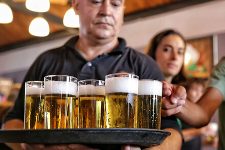 Mozo llevando bandeja con vasos de liso santafesino, símbolo del patrimonio cultural cervecero de Santa Fe