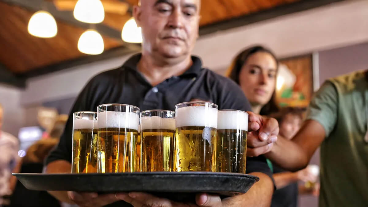Mozo llevando bandeja con vasos de liso santafesino, símbolo del patrimonio cultural cervecero de Santa Fe
