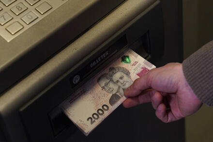 Trabajador escolar extrayendo dinero de cajero automático por cobro del incentivo Asistencia Perfecta en Santa Fe