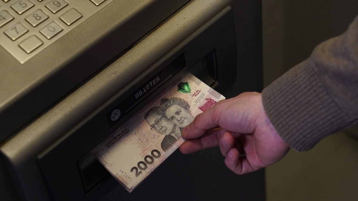 Trabajador escolar extrayendo dinero de cajero automático por cobro del incentivo Asistencia Perfecta en Santa Fe