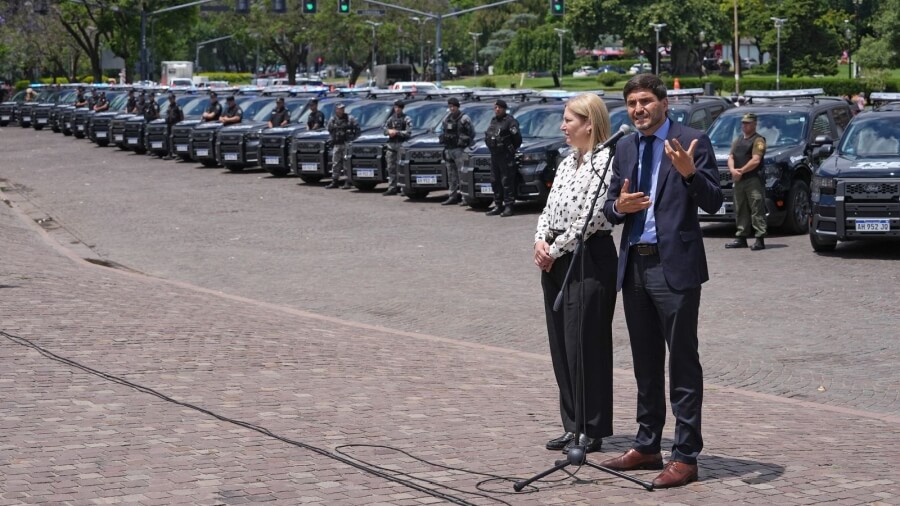 Gobernador Maximiliano Pullaro y vicegobernadora Gisela Scaglia en la entrega de patrulleros nuevos con camionetas 0 km al fondo en Rosario