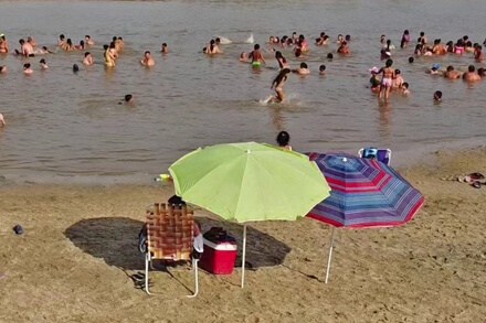 Playa de Romang con visitantes disfrutando del río, la arena y la temporada de verano