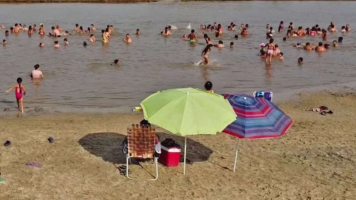 Playa de Romang con visitantes disfrutando del río, la arena y la temporada de verano