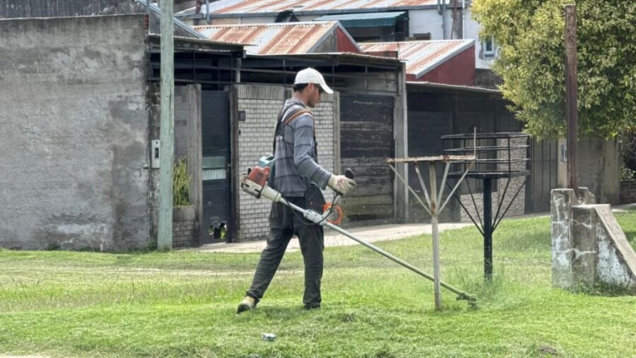 Empleado municipal realizando corte de pasto en barrio Libertad como parte del mantenimiento urbano en Avellaneda