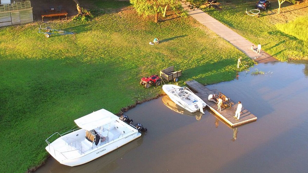 Turistas disfrutan del río en la Costa Santafesina con lanchas y botes anclados junto a una cabaña a orillas del corredor de la Ruta Provincial 1