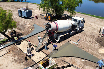 Proceso de hormigonado de badenes en la calle Moreno, acceso al nuevo Paseo Costanero de Romang, con maquinaria y operarios en obra