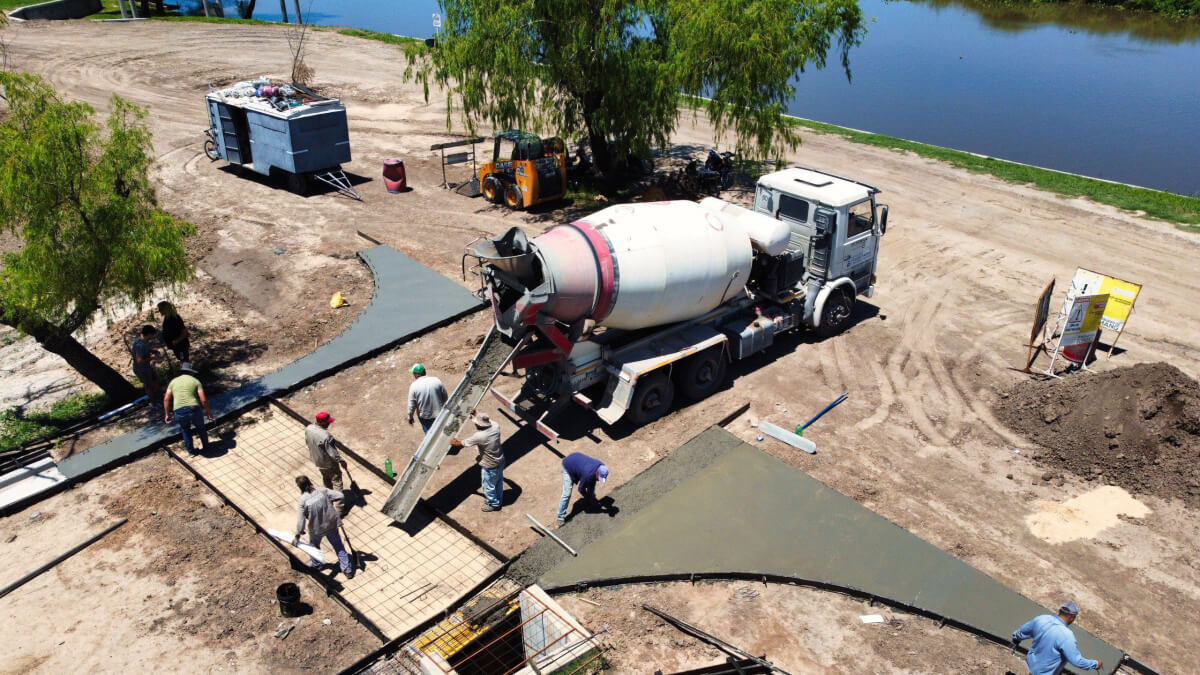 Proceso de hormigonado de badenes en la calle Moreno, acceso al nuevo Paseo Costanero de Romang, con maquinaria y operarios en obra