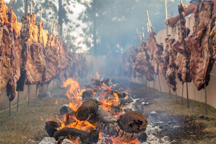 Cocción tradicional del asado a la estaca durante una edición anterior de la Fiesta Regional en El Timbó