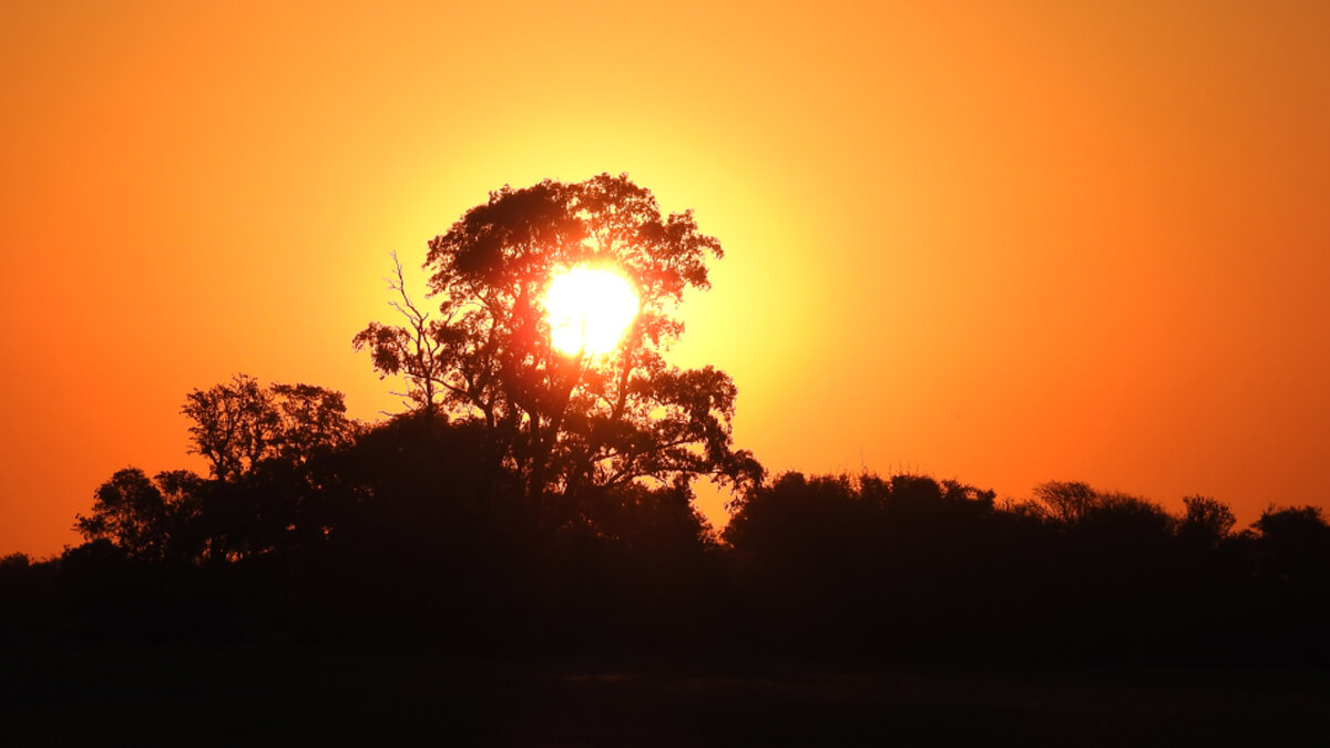 Atardecer de un día caluroso en verano, cielo naranja sobre paisaje argentino, reflejando altas temperaturas y clima cálido