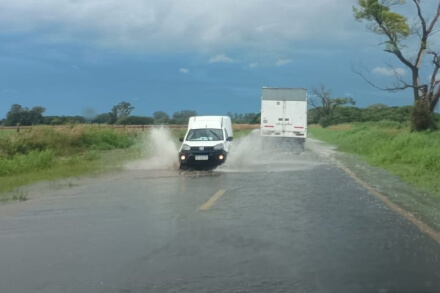 Ruta Nacional 11 entre Nelson y Llambi Campbell con gran acumulación de agua tras intensas lluvias y vehículos circulando con precaución