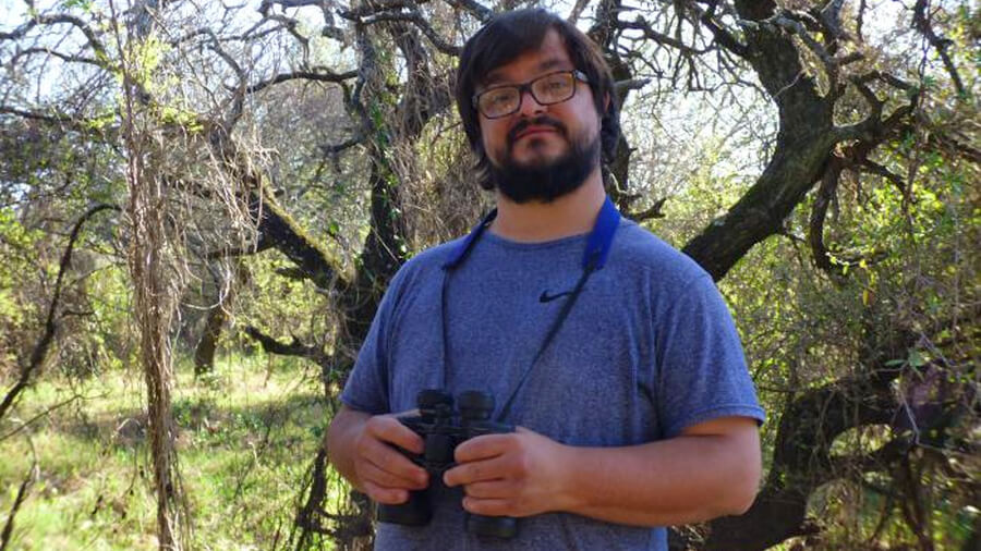 Ornitólogo Pablo Capovilla observando aves en una salida de campo