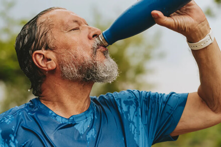 Persona bebiendo agua para hidratarse durante ola de calor, altas temperaturas, cuidado salud