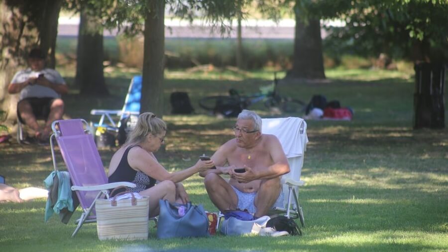Personas a la sombra en un parque durante ola de calor, altas temperaturas y medidas de prevención