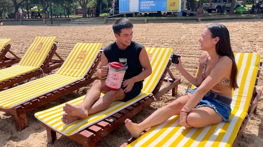 Pareja compartiendo mates tereré sentados en las nuevas reposeras tipo camastro del Camping Brisol en la playa de Romang