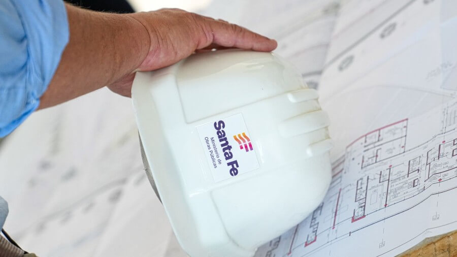 Obrero de la construcción con casco en mano observando plano de obra pública