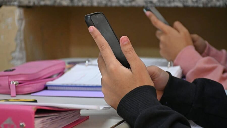 Estudiantes utilizando teléfonos celulares durante una clase en una escuela 