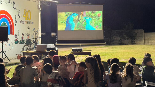 Niños y familias disfrutando de la proyección de la película Río 2 en el CAF Juan Pablo II de Villa Ocampo durante Noches Mágicas
