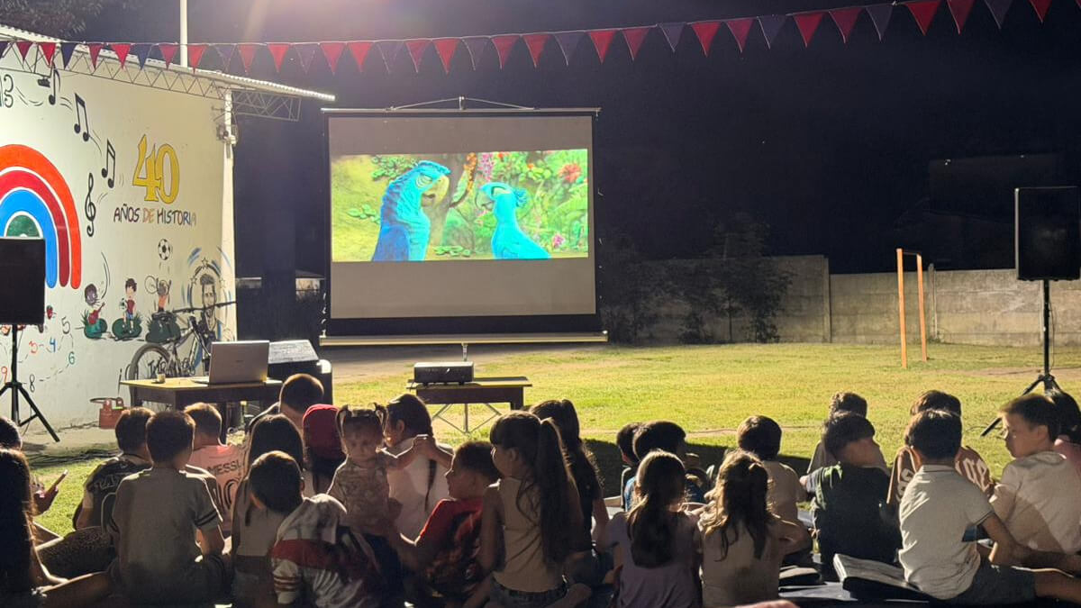 Niños y familias disfrutando de la proyección de la película Río 2 en el CAF Juan Pablo II de Villa Ocampo durante Noches Mágicas