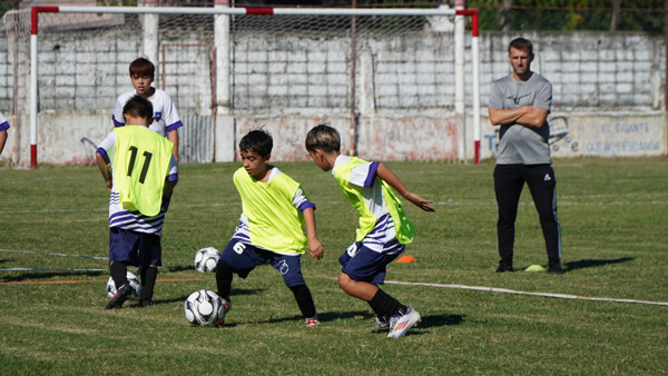 Chicos practicando fútbol infantil en clínica de entrenadores en Villa Ocampo bajo la supervisión de técnicos