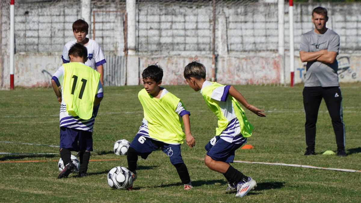 Chicos practicando fútbol infantil en clínica de entrenadores en Villa Ocampo bajo la supervisión de técnicos
