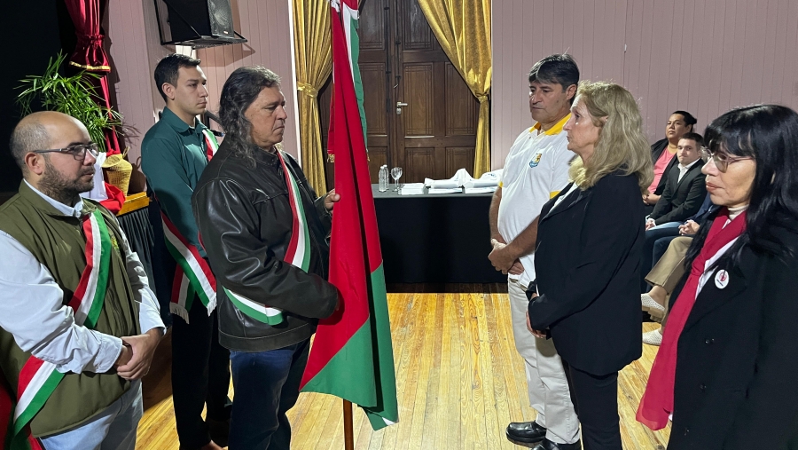 Recambio de abanderados durante el acto oficial por el aniversario de Romang en la Sala Municipal de Cultura, con participación de instituciones educativas.
