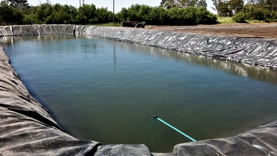 Reservorio de agua rural utilizado para almacenamiento hídrico en campos agrícolas durante eventos climáticos extremos