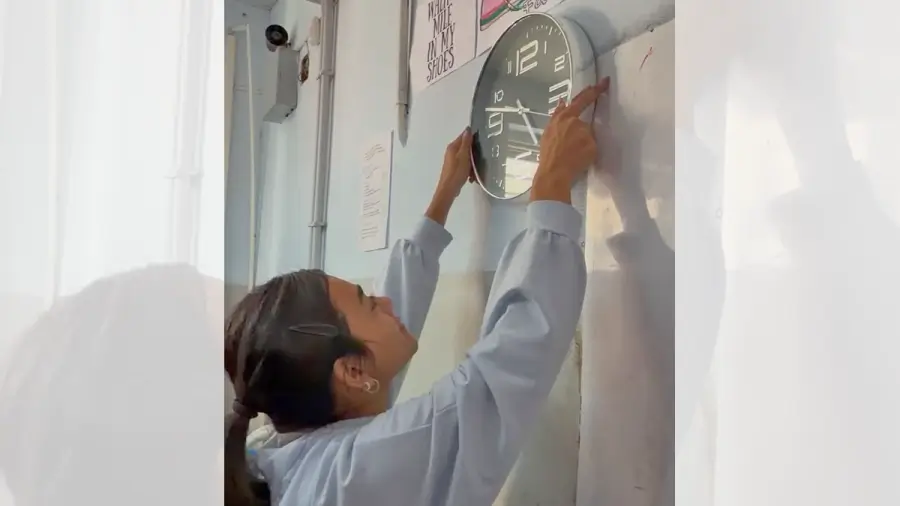 Alumna instala uno de los relojes de pared donados para las aulas de la institución educativa.