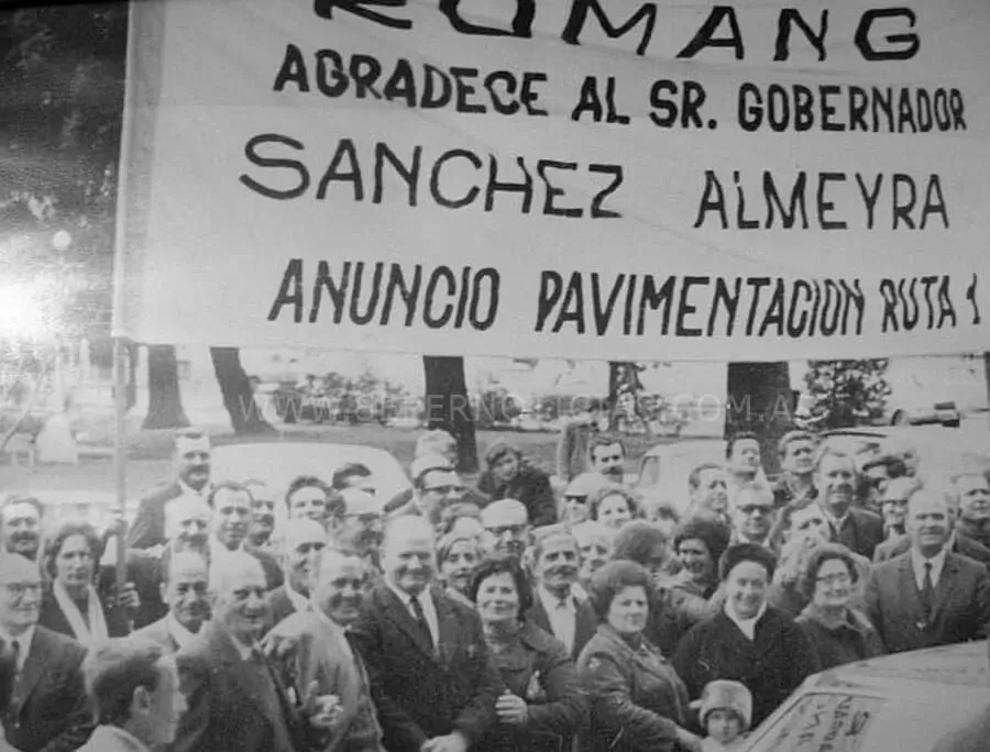 Vecinos de Romang participan del acto de inauguración del pavimento junto a una bandera de agradecimiento