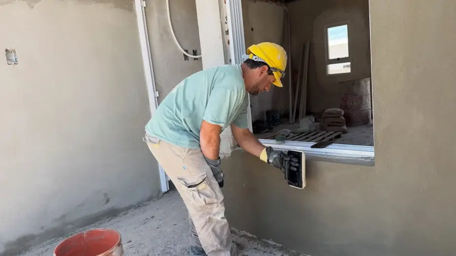 Albañil realiza trabajos de revoque exterior en una de las viviendas en construcción en Lanteri