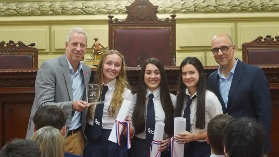 Dionisio Scarpin entrega una distinción a Jazmín Colignon, Camila Suligoy y Martina Kaufmann, creadoras de SynApp, una iniciativa de innovación social de Malabrigo.